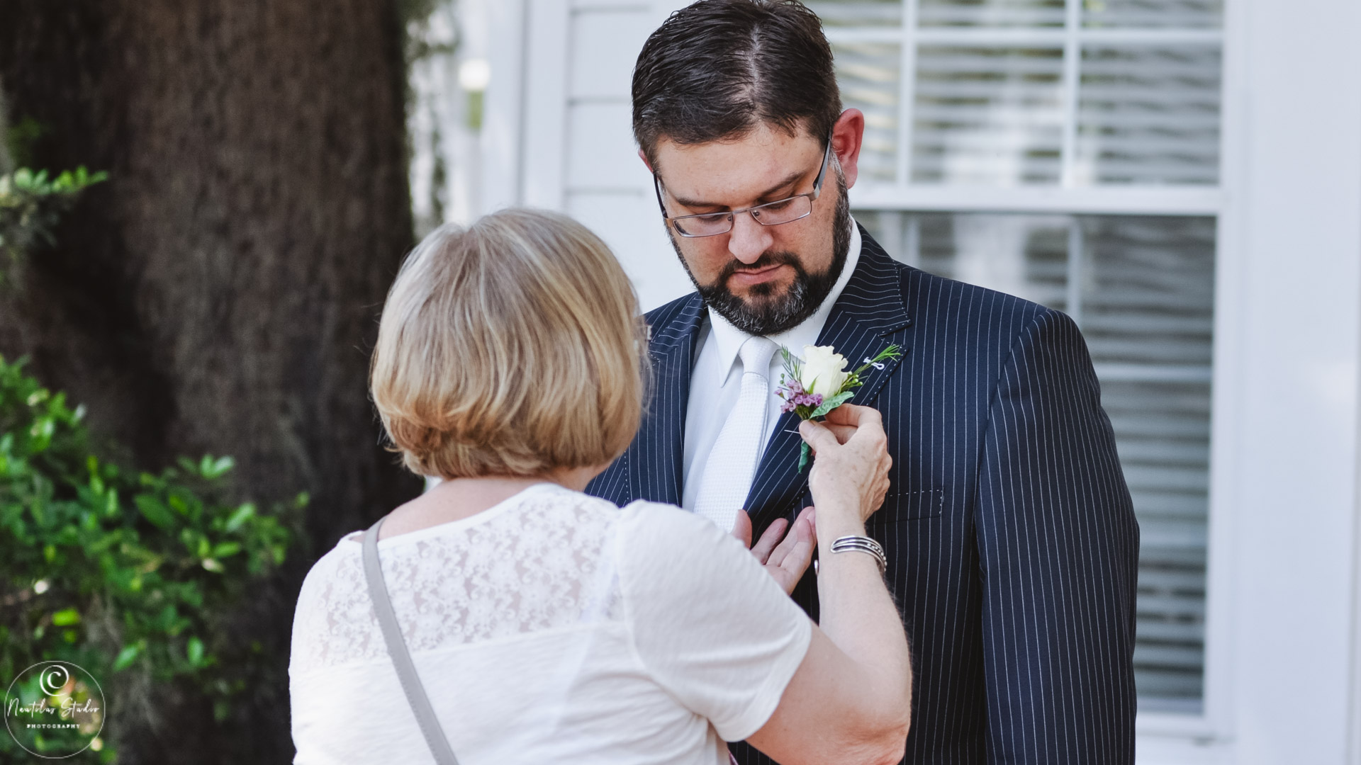 Photo showing mother of groom pinning on boutonniere