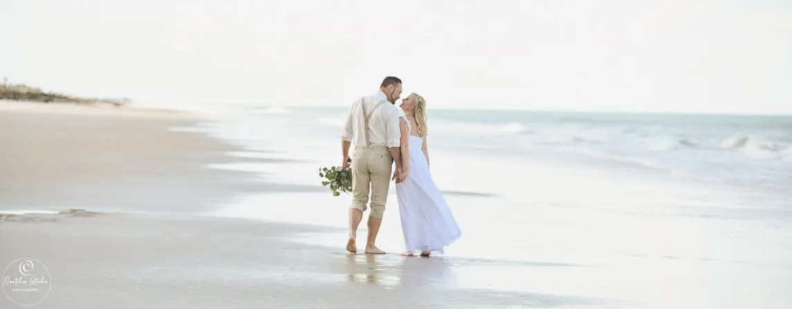 Photo of elopement wedding couple walking down the beach