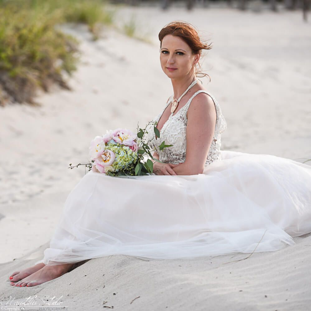 Photo of bride sitting in the sand on her Florida beach wedding in Miami