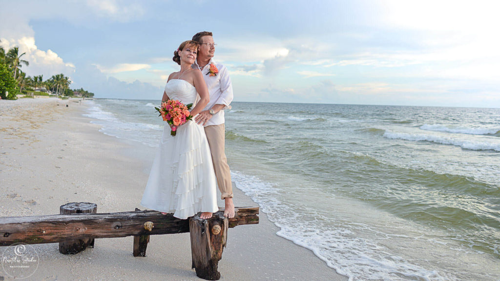 Photo of bride and groom looking out on the Ocean on Naples beach
