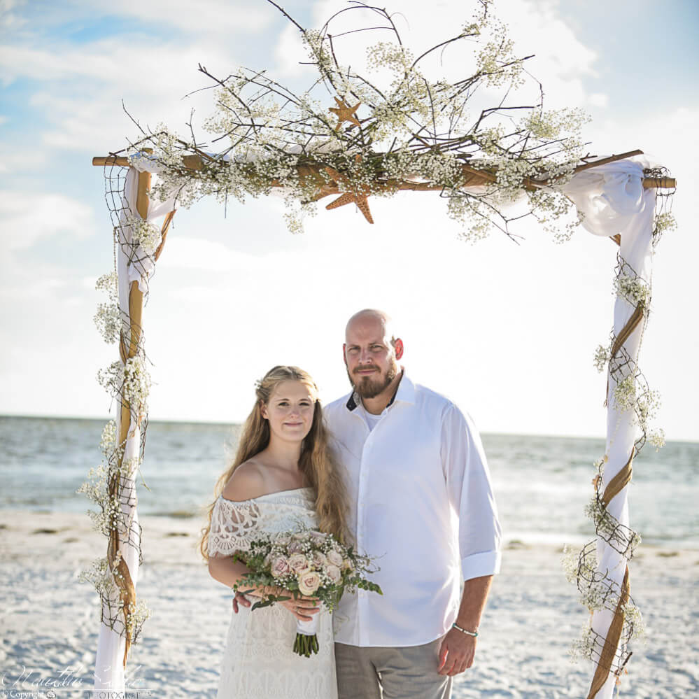 Photo of Bohemian beach wedding arch decorated with babiesbreath