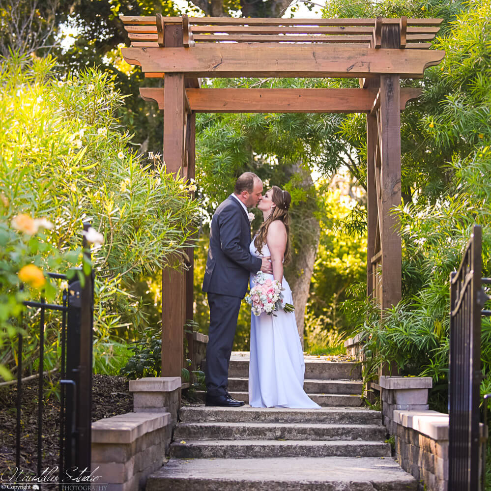 Photo of wedding couple kissing under pergola at Washington Oaks Gardens