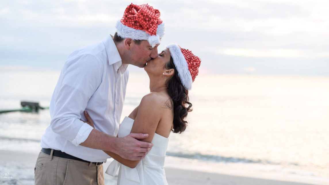 Photo of bride and groom with Santa hats at their elopement wedding in Florida on the beach
