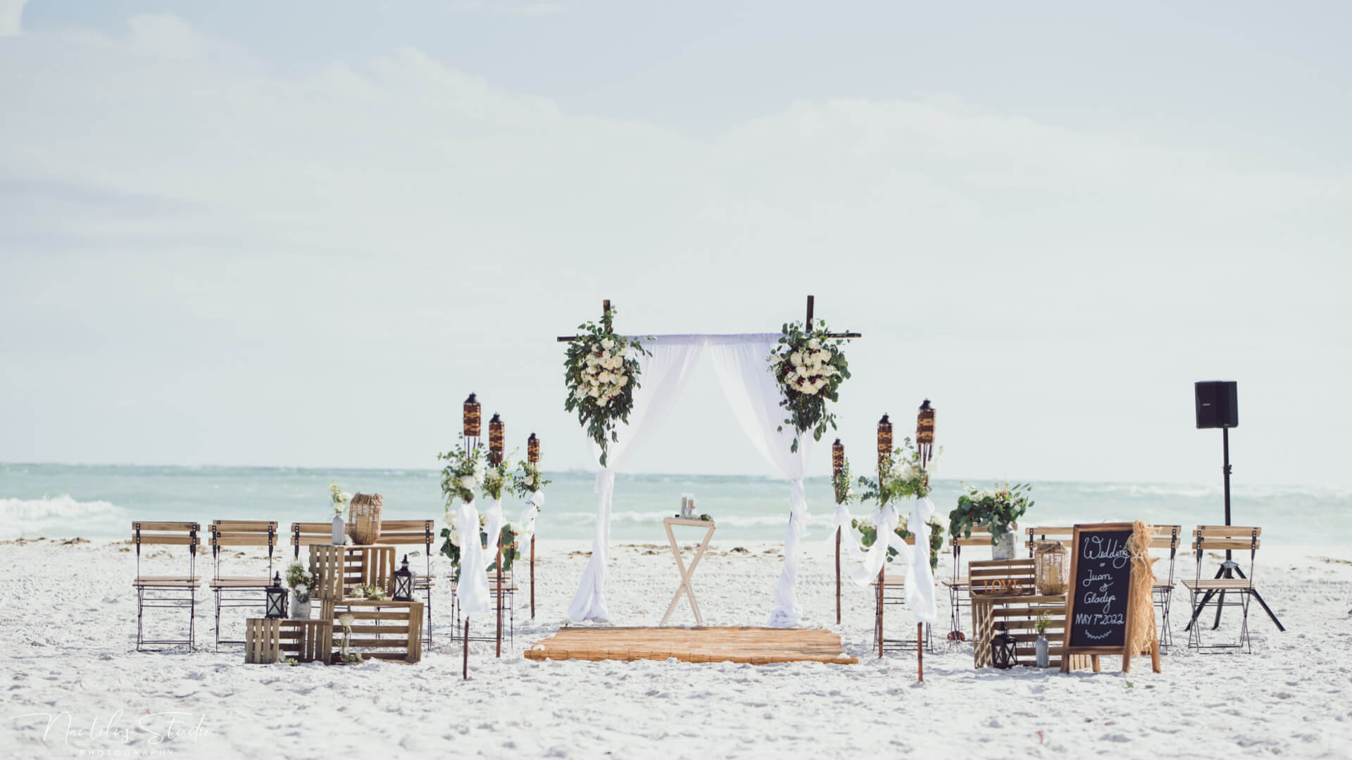 Lifestyle vintage beach wedding decoration with fresh flowers and French Country chairs for guests