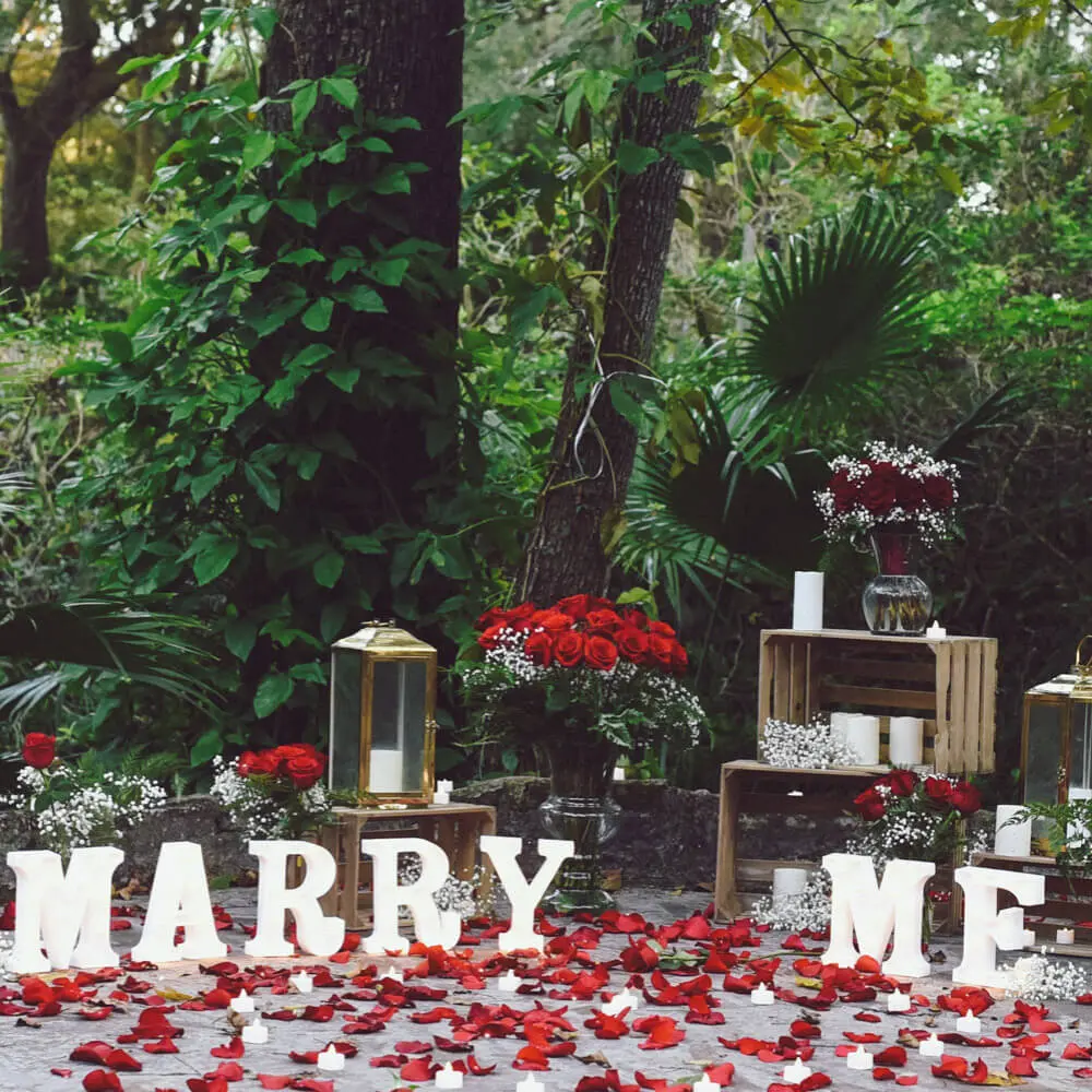 Roses in the park marriage proposal package in Orlando. Photo showing lighted marry me letters and lots of roses and rose petals and decorated wooden crates.