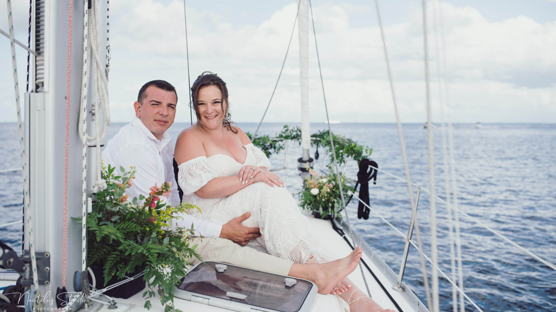 Photo of bride and groom sitting on deck at their exclusive sailboat elopement