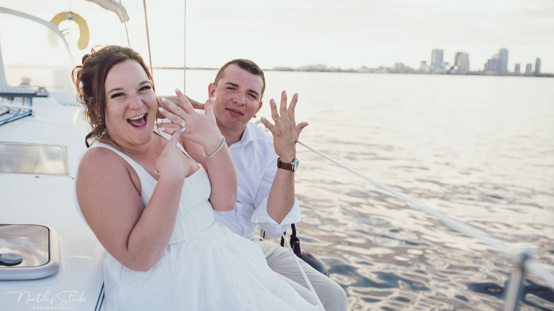 Funny photo of a bride and groom showing their rings at their sailboat elopement