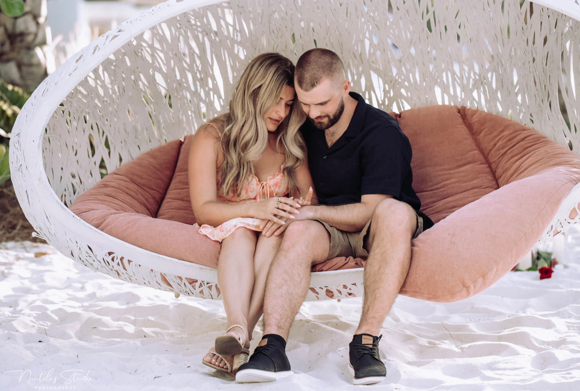Photo of newly engaged couple sitting in a beach swing at the Evermore Resort after his proposal.
